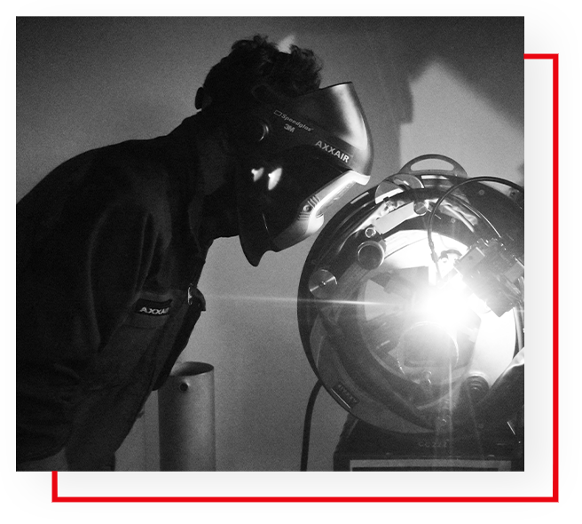 A black and white photo of a man welding.